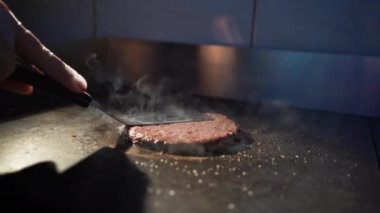 Kızarmış sığır burger pirzolası. Şef sıcak tavada bir burger için kıymalı et hazırlar. Hamburger pişirme konsepti