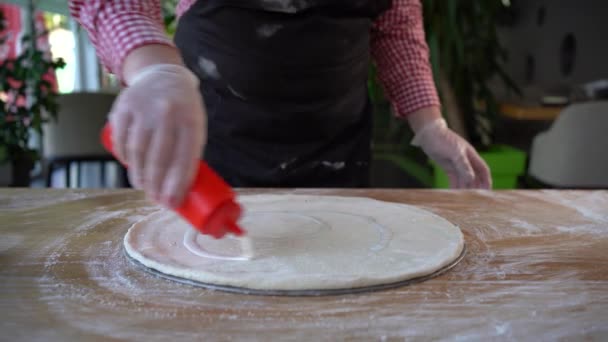 Chef-kok giet witte saus over pizza deeg. Pizza bakker zet saus. — Stockvideo