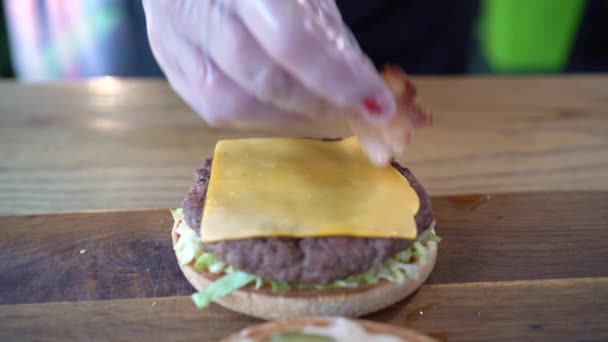 여성 손으로 햄버거를 만들고 있습니다. 패스트푸드. — 비디오