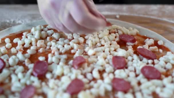 Cuoco per cucinare la pizza, spalmare salumi sulla mozzarella, pasta cruda. Pizza tradizionale italiana. Il concetto di preparazione di cibo fatto in casa. — Video Stock