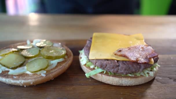 Μαγείρεμα μπέργκερ, κοντινό πλάνο. Σεφ κάνει ένα burger από τα συστατικά, κορυφαία άποψη. Χάμπουργκερ με μπέικον και μοσχάρι. Fast food εστιατόριο. — Αρχείο Βίντεο