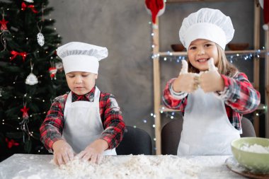 Mutlu aile, çocuklar hamuru hazırlar, mutfakta zencefilli ekmek pişirir, kız ve erkek Noel kurabiyeleri hazırlar. Şenlik arka planı. Boşluğu kopyala