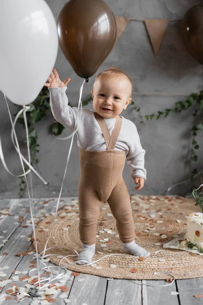 First birthday of the child, happy one year old toddler with balls. Rustic style childrens birthday concept.