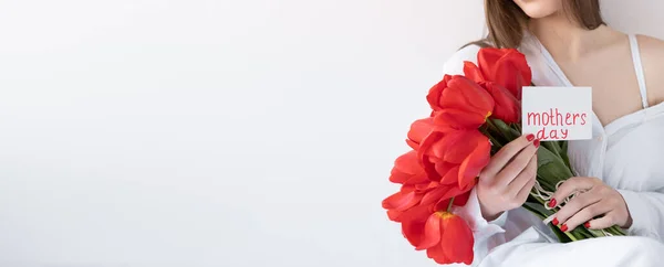Květiny na Den matek. Dívka s tulipány a pohlednicí na bílém pozadí. Šťastný Den matek. Nápis — Stock fotografie