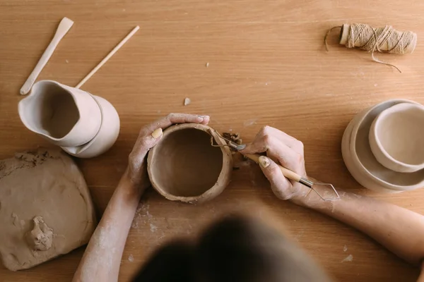 Cerámica en concepto de arte de arcilla taller. primer plano en las manos de un joven ceramista con una olla de barro sin cocer. manos artesanales lugar de trabajo sostienen una taza de arcilla —  Fotos de Stock