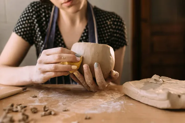 Mujer alfarera trabaja con arcilla en su taller de casa, manos del maestro de cerca, amasa y esculpe arcilla antes del trabajo, enfoque selectivo. hobby creativo — Foto de Stock