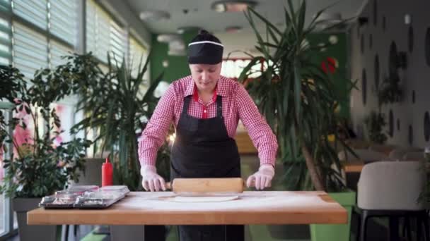 Pizzeria chef che cucina pizza italiana, panettiere stende l'impasto con un mattarello sul tavolo, donna che cucina la pizza margarita in un ristorante. — Video Stock