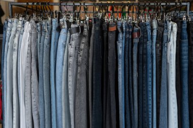 Yakın plan, elbise mağazasında askıda asılı kot pantolon markalı ürünlerin satışı, kot üretim departmanı. Giysi arkaplanı