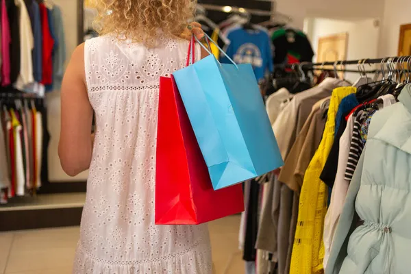 Giyim mağazasında ya da butikte alışveriş yapan sarışın bir kadının, kadın giyim mağazasında ürünleri olan bir müşterinin, bayram indirimi ve mutlu bir alışveriş düşkününün arka plan görüntüsü..
