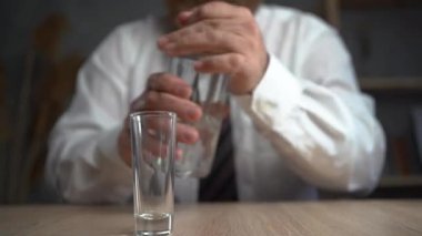 Şişeden bardağa alkol döken bir adamın yakın çekimi. Alkol bağımlılığı, alkolizm kavramı. Sarhoş iş adamı.