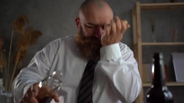 Alkol bağımlılığı, iş yerinde içki içen adam. Depresyondaki sakallı alkolik. İş adamı stres içinde bir bardak viski içer.. — Stok video