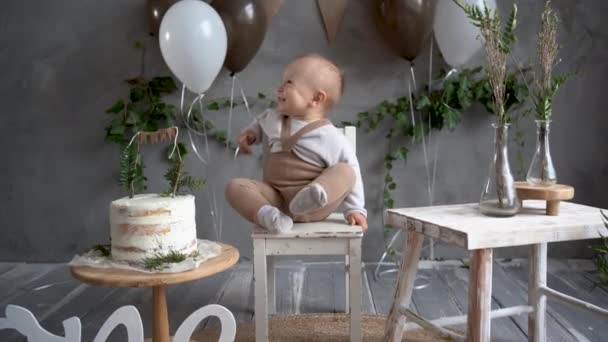 Első boldog szülinapos gyerek ünnepi hátterű lufik és torták, születésnap egy év rusztikus stílusban, kisfiú ül egy névnapi széken, kisgyerek fotó. A gyermekek születésnapja. — Stock videók
