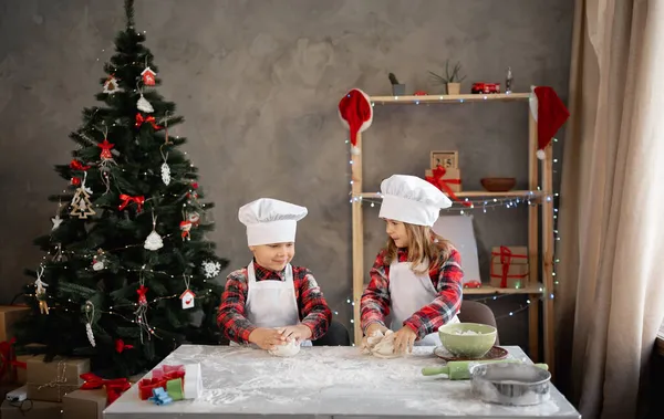 Evde noel kurabiyeleri pişirmek, çocuklar zencefilli ekmek pişirmek, Noel arifesinde yemek hazırlamak, arkadaş canlısı erkek ve kız kardeşler mutfakta, şenlikli duvar arkaplanı.