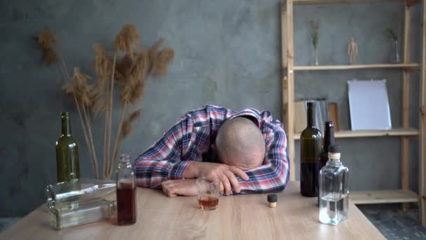 En deprimerad berusad man som håller en drink och sover hemma vid bordet. begreppet depression och alkoholism i muskeln. — Stockvideo