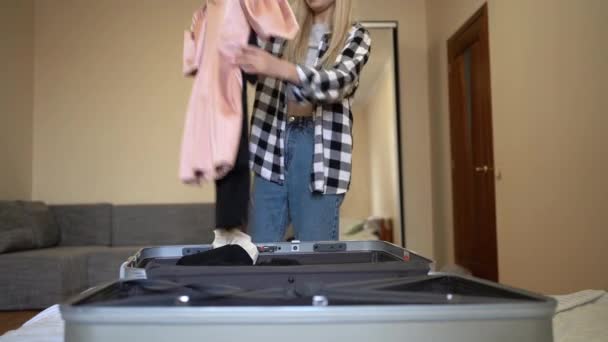 이 여성은 호텔에서 여행 가방을 분해하고 옷을 꺼내 옷장에 걸어 둔다.. — 비디오