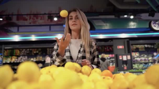 Femme caucasienne se tient dans un supermarché et choisit joyeusement citrons à acheter. — Video