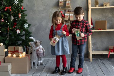El yapımı takvim paketleri çocukların elinde, Noel için el sanatları, mutlu çocuklar, Noel arifesinde erkek ve kız kardeşler bir numaralı paketle, el sanatları konsepti, kopyalama alanı.