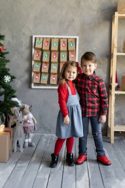 El yapımı takvimin arka planında küçük erkek ve kız kardeşlerin portresi, Noel dekoru olan çocuklar, tatil için çocuk el sanatları. Çocukların Noel geleneği konsepti.