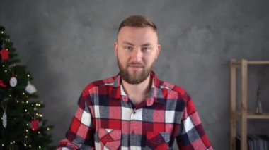 Noel yemeği için pizza teslimatı, sakallı adam masada otururken bir kutu pizza açıyor, gri arka planda Noel ağacı, yemek servisi...
