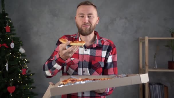 Concept de livraison de pizza, homme barbu mange une délicieuse pizza chaude pour le dîner de Noël, nourriture parfumée à la maison, repas de restauration rapide — Video