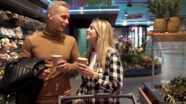 Genç evli çift süpermarkette alışveriş yapıyor, konuşuyor ve kahve içiyor, pazarda alıcı erkek ve kadın.