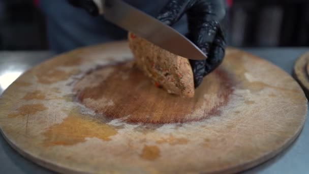 Koch schneidet Hühnerfilet mit einem Messer, gebackenes Fleisch wird auf einem Holzbrett geschnitten. Kochen zu Hause. Hände von Köchen, Nahaufnahme — Stockvideo