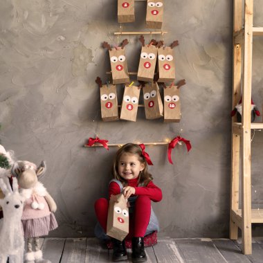 Mutlu kız Noel hediyesiyle el çantası açıyor, çocuk bir mucize bekliyor, Noel aile gelenekleri konsepti.