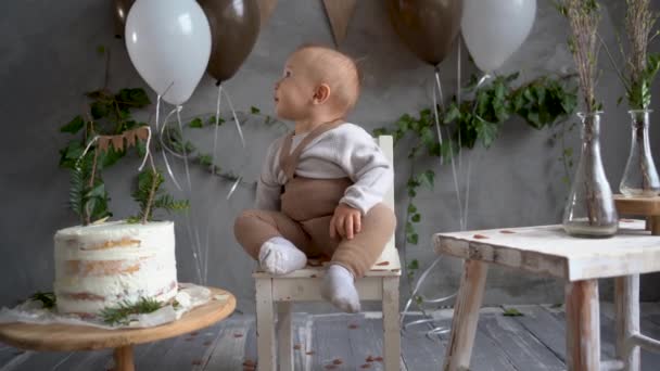 Urodziny dzieci w stylu rustykalnym, dziecko siedzące na krześle tło balonów i flag, konfetti nad chłopcem, roczne dziecko, pierwsze urodziny — Wideo stockowe
