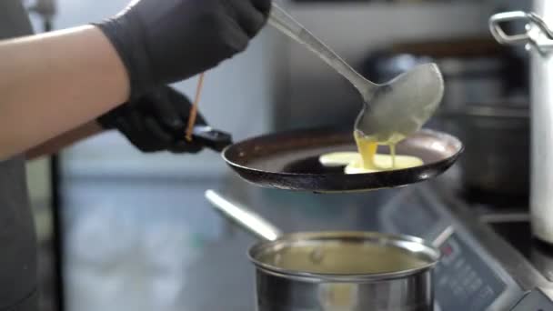 Stek pannkakor till Shrovetide. Kocken häller smeten i stekpannan och fördelar den jämnt. — Stockvideo