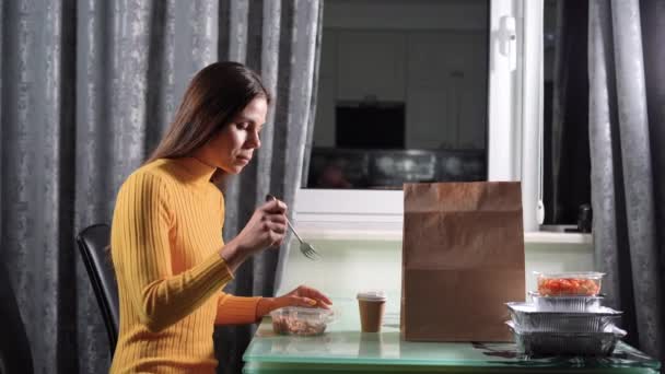 Conceito de entrega de alimentos em casa, menina jantando com alimentos em recipientes de plástico em casa, refeições em utensílios de mesa descartáveis — Vídeo de Stock