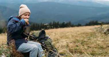 Dağlarda bir turistin kahvaltısı. Gezgin özel yemekler yiyor. tepe boyunca yolculuk. Turist yemekleri konsepti. Atıştırmalık fast food ve dağlarda rahatlama. Pankart
