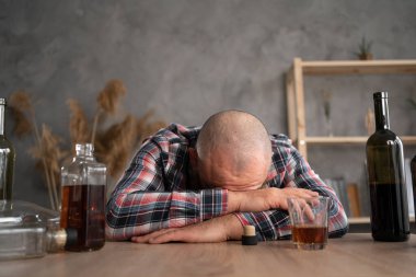 Alkol bağımlılığı, alkol bağımlılığı ve insanların konsepti. Alkolik bir adam gün boyunca boş içki şişelerinin arasında yatıp kalkıyor. Boşluğu kopyala.