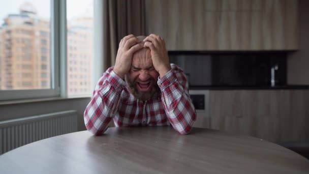 Sorglig och orolig 40-tals man med skägg sitter vid bordet hemma, ser deprimerad och förkrossad med sorg med ansiktsuttryck i depression och livsproblem koncept. — Stockvideo
