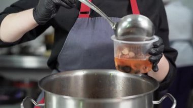 Yemek servisi. Restoranda, şef yemeği hazırlar ve tek kullanımlık yemeklerde hazırlar. Yakın plan kadın elleri, sosisli çorbayı beslenme çantasına döker..