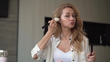 Güzellik, kozmetik, e-ticaret ve blog konsepti. Güzel, profesyonel bir makyaj sanatçısı çevrimiçi öğrencilere pudranın yüzüne nasıl sürüleceğini öğretiyor ve gösteriyor..