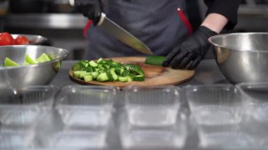 Yemek dağıtım servisi. Bir kadın eli, kesme tahtasındaki bir bıçakla çiğ salatalık keser. Çevrimiçi sipariş ve teslimat konsepti. Lezzetli, sağlıklı, dengeli, hazır yemek..