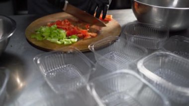 Yemek dağıtım servisi. Bir kadın eli kesme tahtasındaki bir bıçakla çiğ kırmızı biber keser. Çevrimiçi sipariş ve teslimat konsepti. Lezzetli, sağlıklı, dengeli, hazır yemek..
