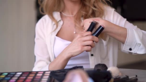 Beleza, cosméticos, e-commerce e conceito de blog. um artista de maquiagem profissional fala sobre cores de batom durante a gravação de uma revisão de vídeo de produtos de beleza em casa. sem rosto. — Vídeo de Stock