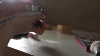 Bej tozlu makyaj fırçası. Bir fırça üzerinde toz toplayan kadın ellerinin yakın çekimi.