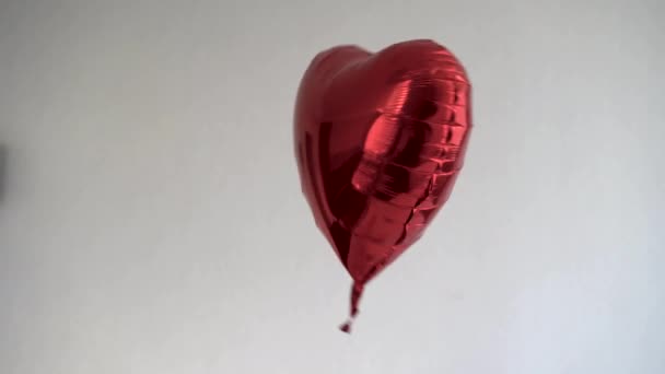 Rode ballon met helium in de vorm van een hart op een lichte achtergrond. — Stockvideo