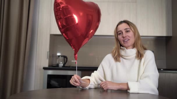 Mujer que tiene una videollamada en el portátil muestra un corazón globo. Citas a distancia. Videollamada del usuario milenario de Internet. Día de San Valentín. — Vídeos de Stock