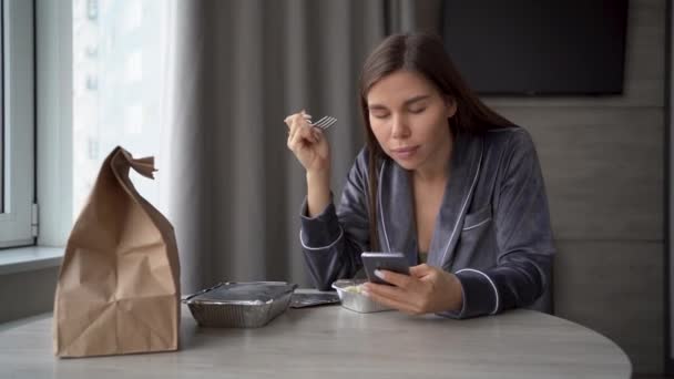 Smiling woman eating healthy food while using her cell phone at home. take pictures of your breakfast for subscribers. — 图库视频影像