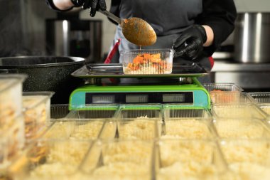 Restorana yemek teslimatı. Elektronik ölçekte bir yığın pirinci tartan eldivenli bir şefin elinin yakın çekimi. Küçük bir iş. Paket yemek. Boşluğu kopyala.