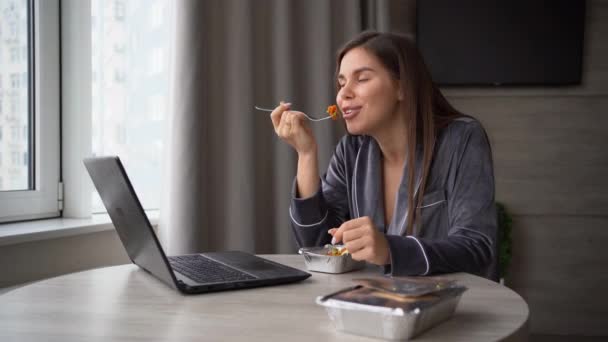 Evdeki masada oturan genç ve güzel bir kadın tek kullanımlık kasede yemek yiyor. Bilgisayarla video görüşmesi yapıyorum. Paket yemek, market teslimatı..