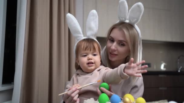 Happy mother and preschool child painting Easter eggs sitting at the table. Easter craft. A mother and her daughter are painting Easter eggs. Happy family is preparing for the holiday. — Video Stock