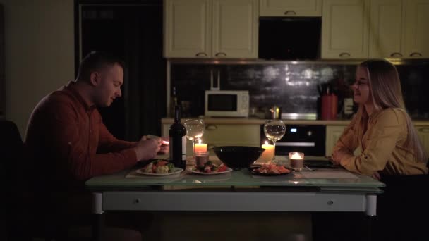 Romantica cena a lume di candela a casa. Un uomo e una donna si siedono a un tavolo in una data per festeggiare San Valentino il 14 febbraio o anniversario.. — Video Stock