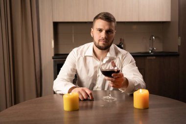 Sevgililer günü için romantik bir akşam yemeği, 14 Şubat 'ta şarap ve mumlarla dolu bir masada bir adam, yalnız bir tatil günü aşk günü, şarap kadehli bir milenyum erkeğinin portresi, mutlu sevgililer günü konsepti