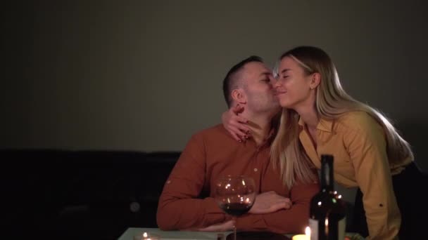 Romantic dinner at home by candlelight for an anniversary, anniversary or Valentines Day. beautiful girl caring for a guy puts vegetables on his plate. date at home concept. — Wideo stockowe