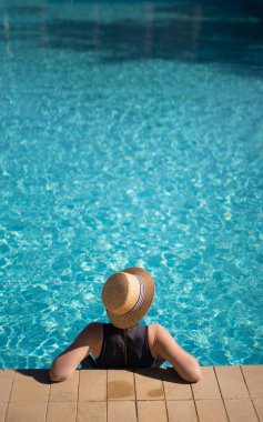 Young asian woman in hat relaxing in swimming pool spa resort, top view. vacation and relaxation concept. vertical banner, place for text
