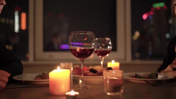 Romantic candlelight dinner. Young couple sitting at a table on top of each other and lovingly toasting toast with wine. Concept for celebration of valentines day, anniversary or anniversary. — Stok video